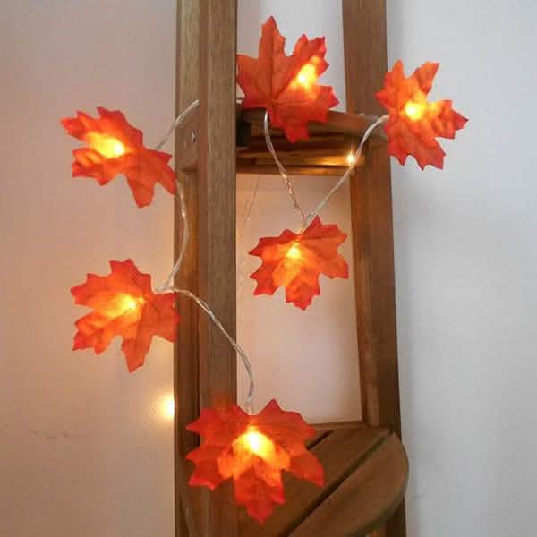 Lighted fall leaf LED string lights on a wooden post with warm glowing orange maple leaves