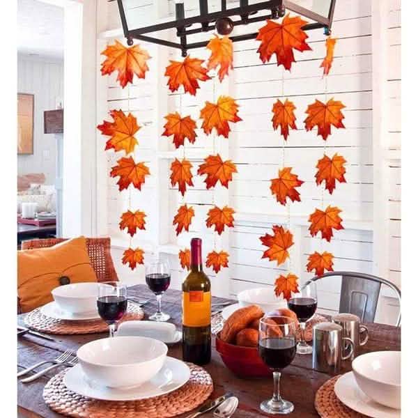 Lighted fall leaf LED string lights hanging above a dining table with glowing orange leaves