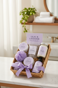 Lilac and lavender spa gift basket with labeled jars, bath items, and ribbon bow