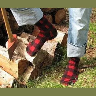 Red and black buffalo plaid crew socks on legs outdoors, fuzzy fleece with ribbed cuff.