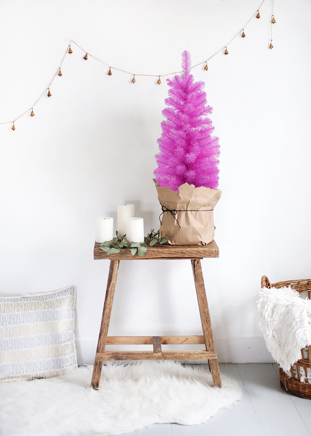 Pink tabletop Christmas tree on stand with string lights overhead