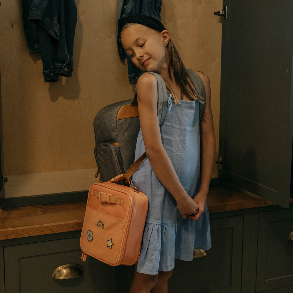 Orange insulated kids' lunch box with front patches and adjustable shoulder strap