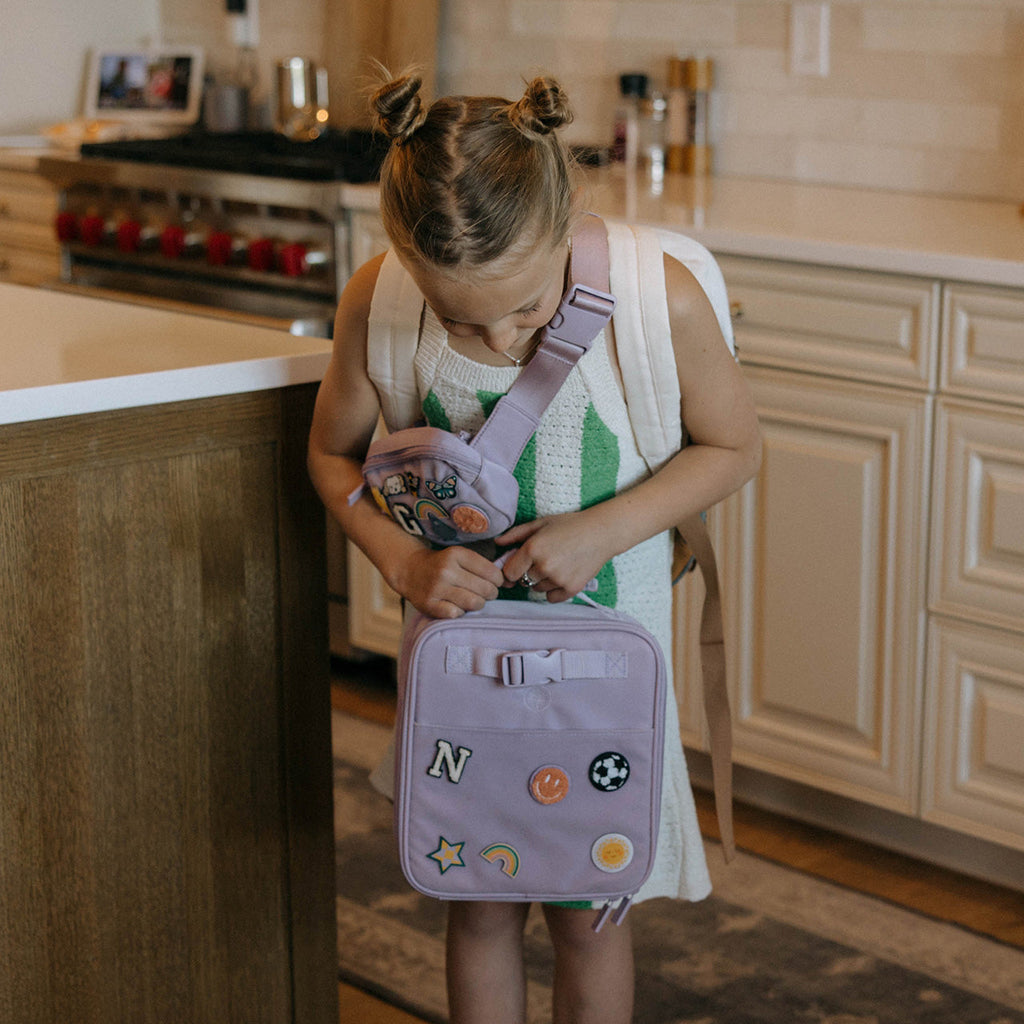 Kids lunch box bag in lavender with adjustable shoulder strap and patch details