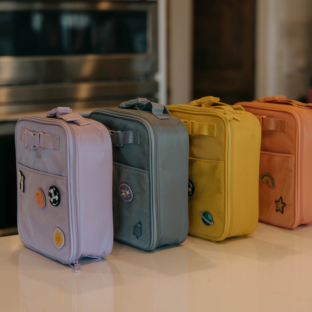 Set of insulated kids' lunch boxes in pastel colors, standing side by side