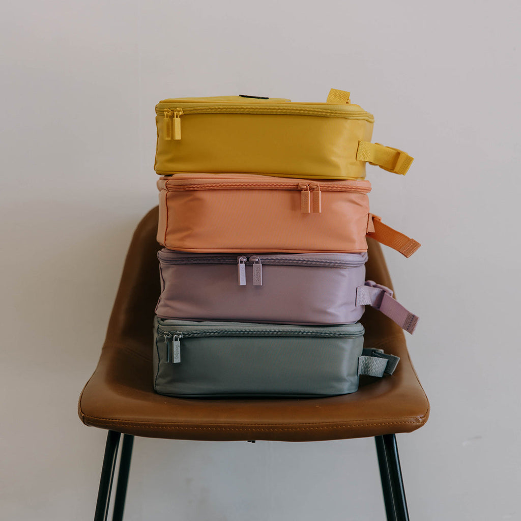 Stack of insulated kids lunch boxes in yellow, orange, purple, and green tones