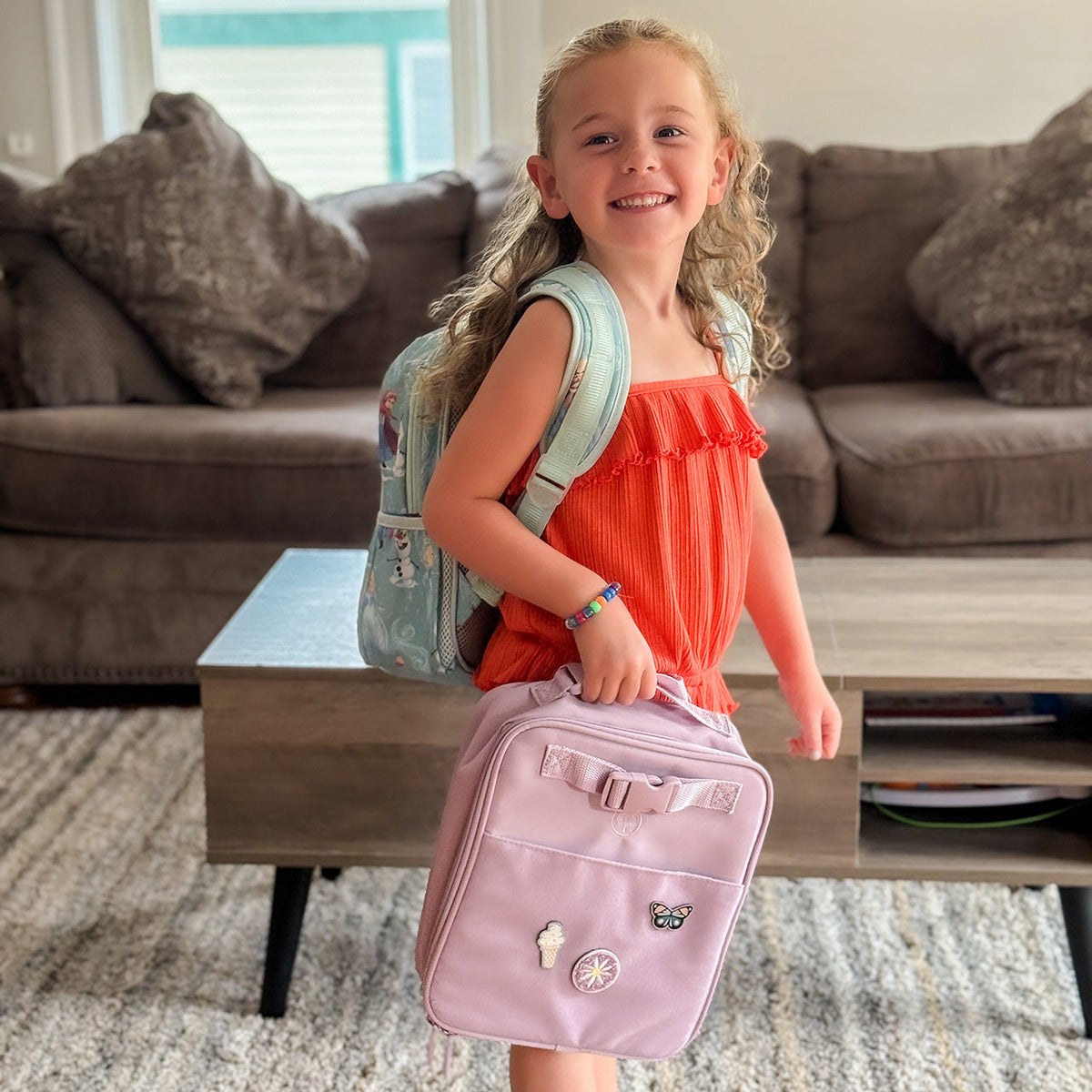Pink insulated kids' lunch box with front zipper pocket and stitched detail