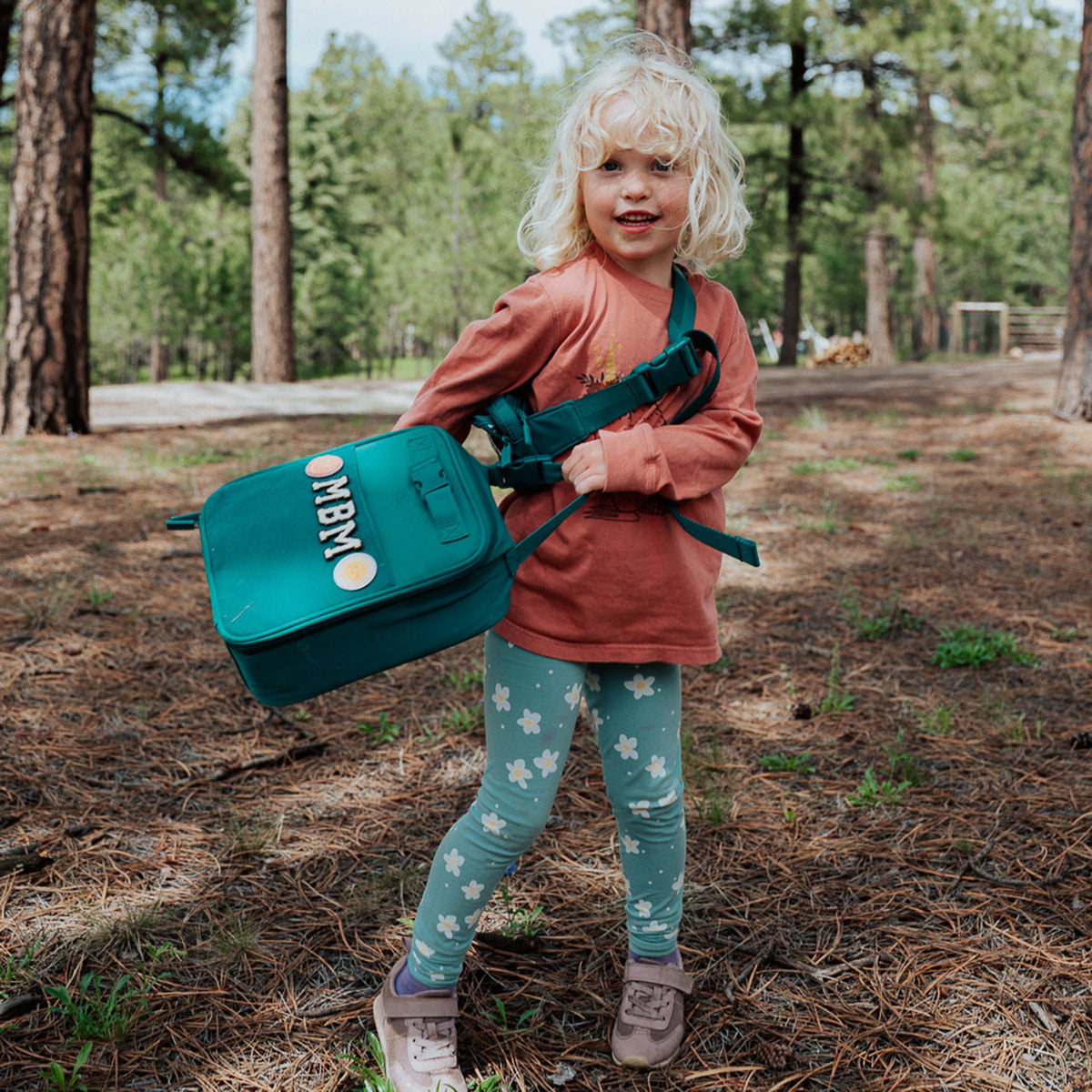 Kids lunch box bag in teal with adjustable strap and “Out” patch on front