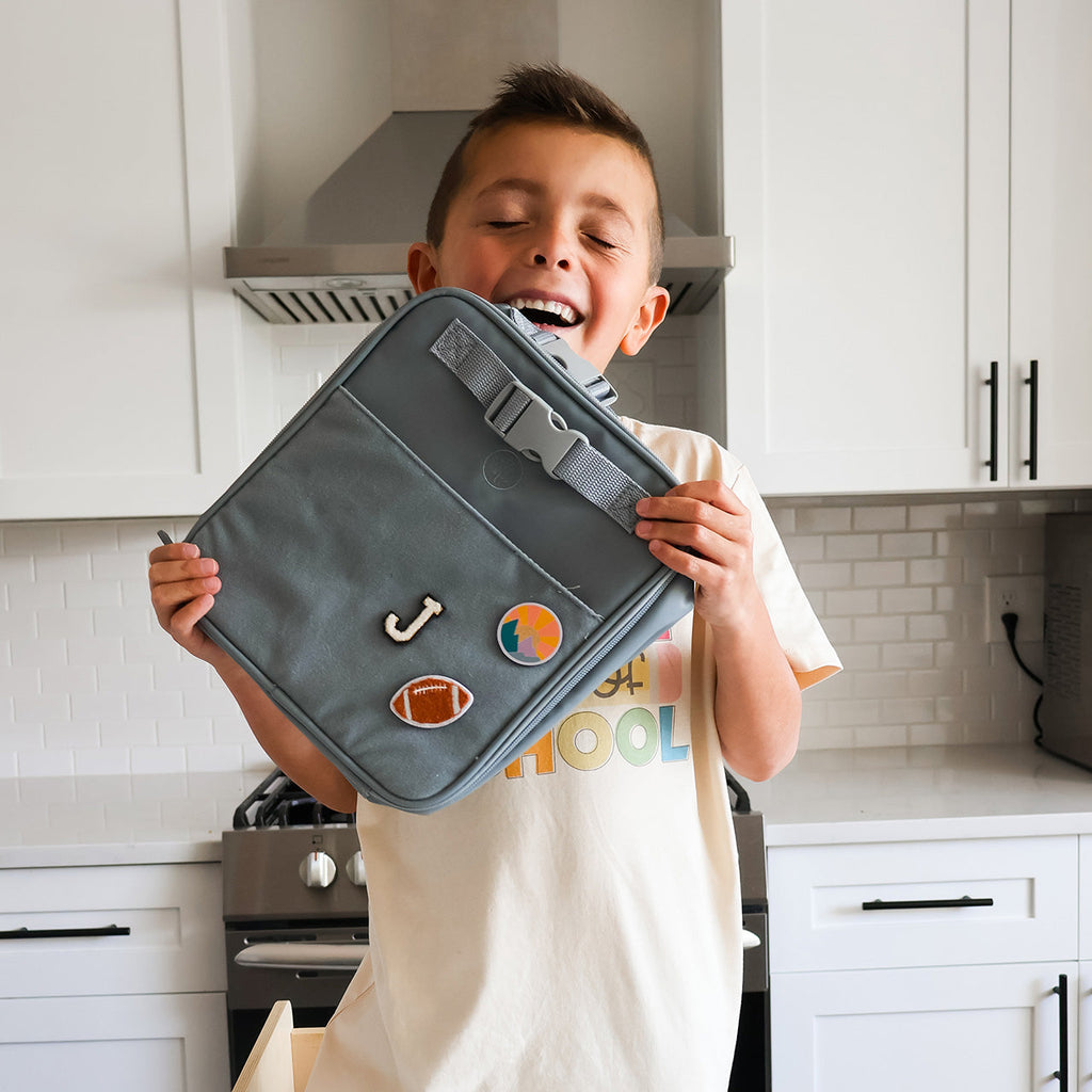 Slate blue kids lunch box with top handle and colorful fabric patches