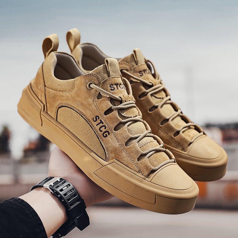 Tan lace-up sneakers with STCG logo and chunky rubber sole, held in hand