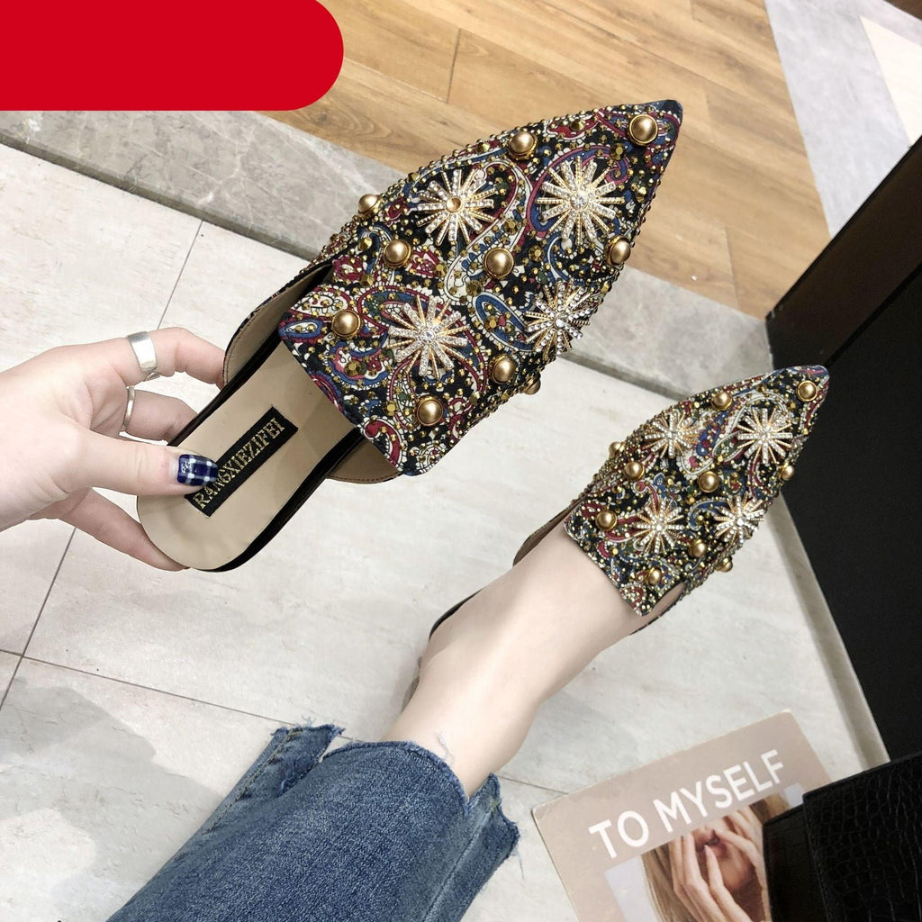 Embellished pointed-toe slip-on mules, dark base with gold and jewel-like accents.