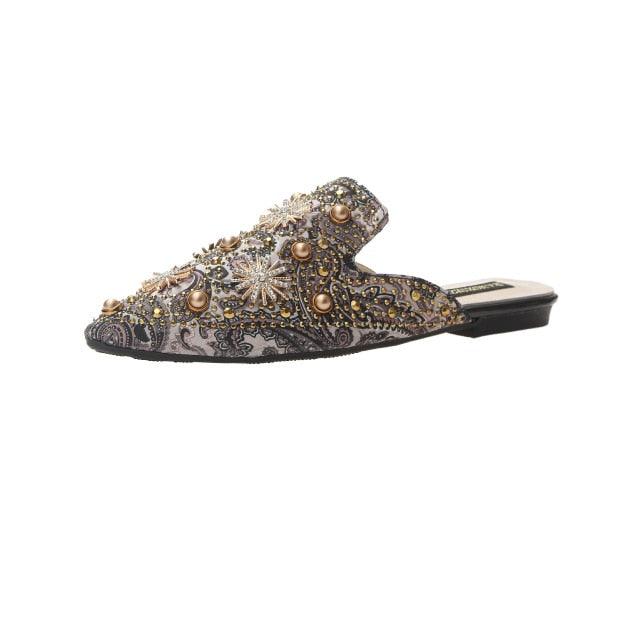Beaded pointed-toe flat mules with ornate starburst pattern and stud details.