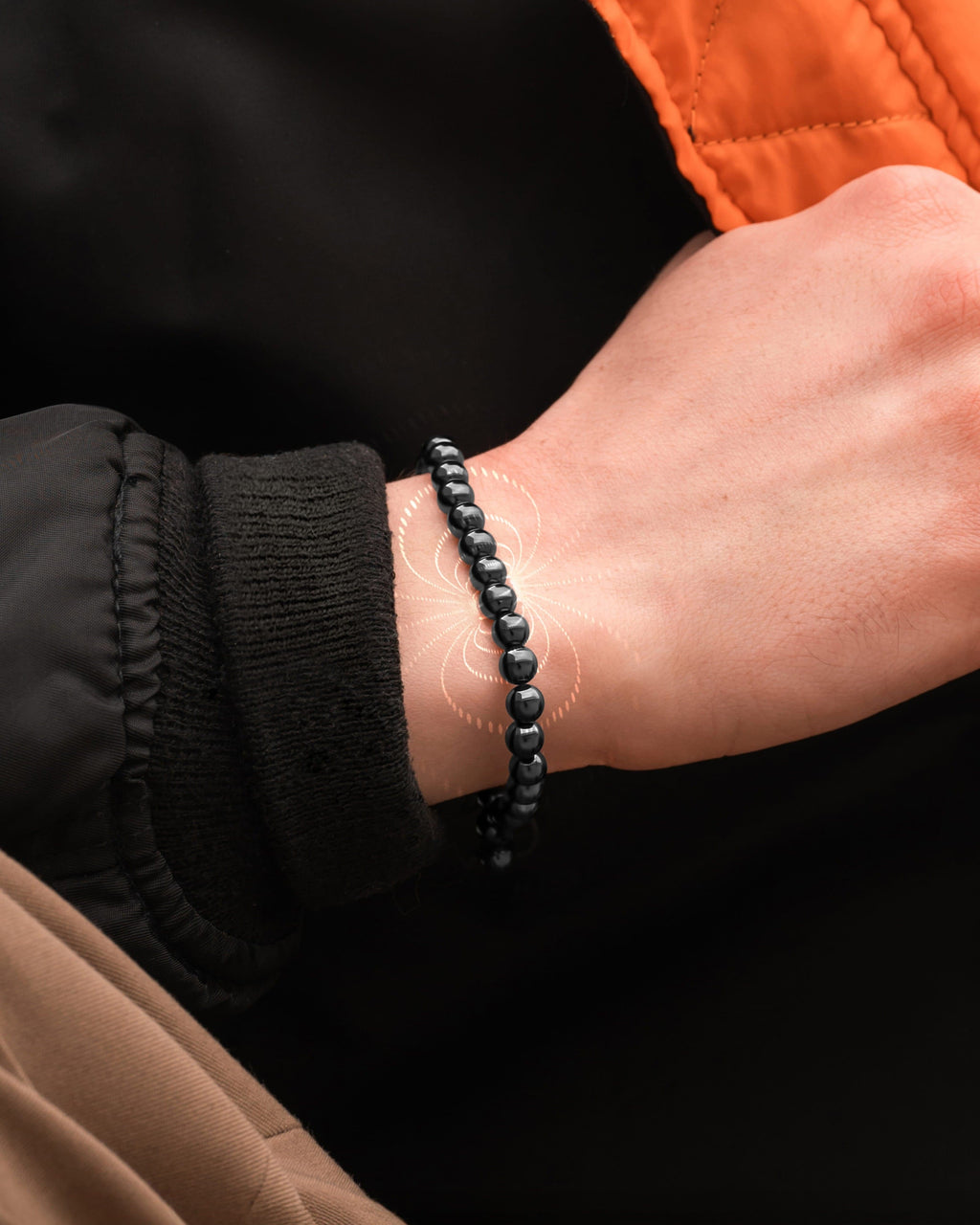 Close-up of hematite bead magnetic bracelet on wrist with black cord charm
