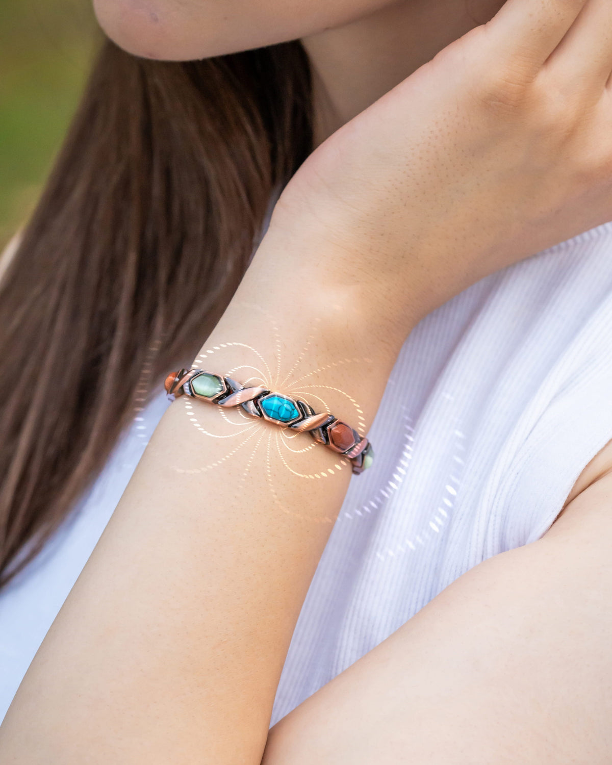 Copper magnetic bracelet on wrist with blue turquoise and red stone accents.