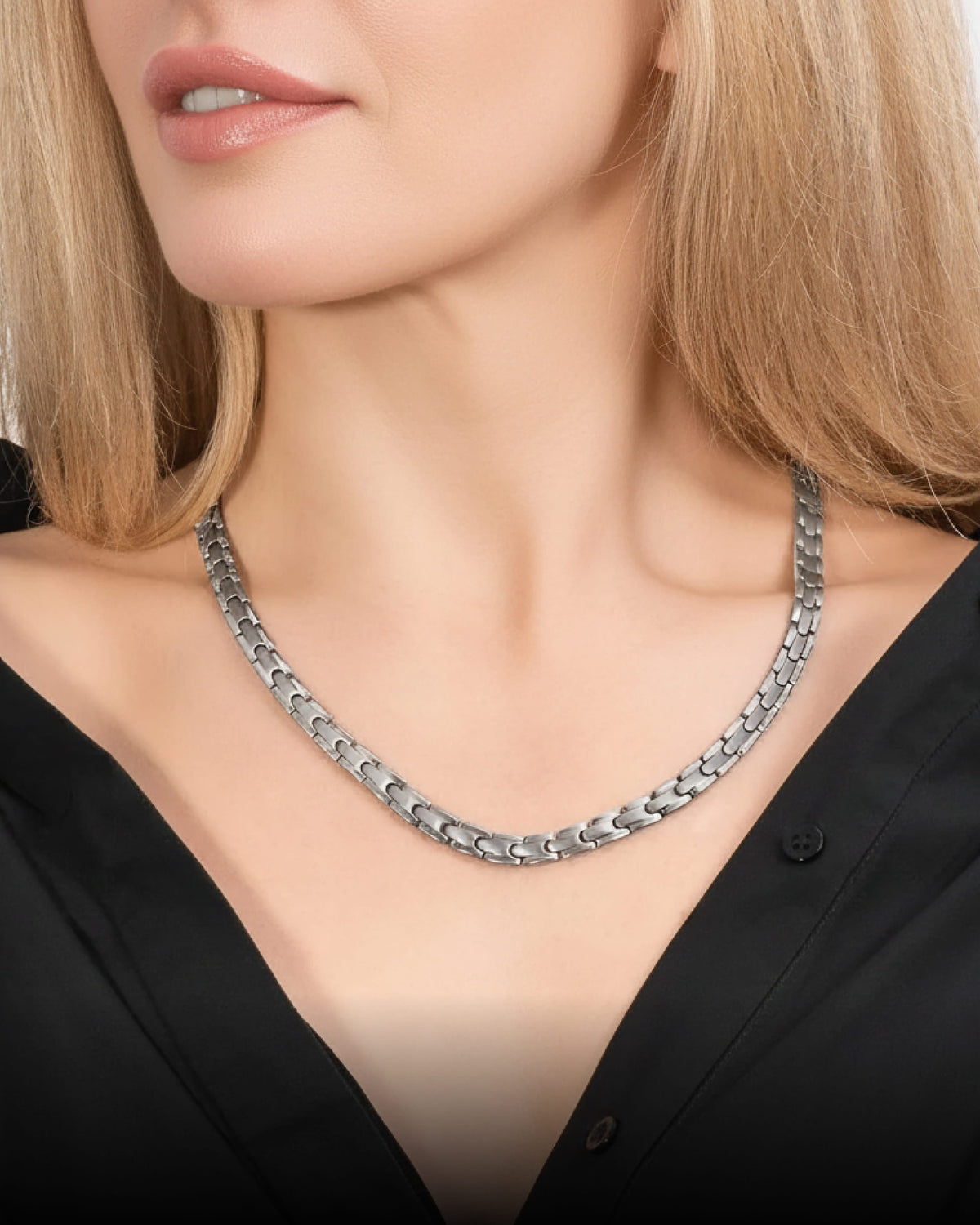 Silver link magnetic therapy necklace worn on a woman's collarbone, close-up