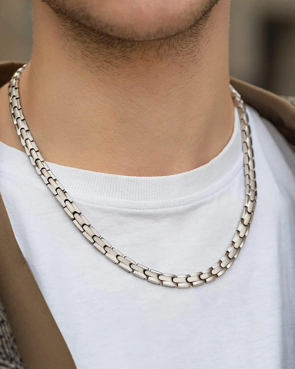 Silver link magnetic therapy necklace worn on a man's neck, close-up view