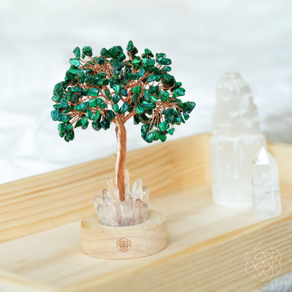 Close-up of malachite crystal tree lamp on light wood with teal branches and clear crystal base.