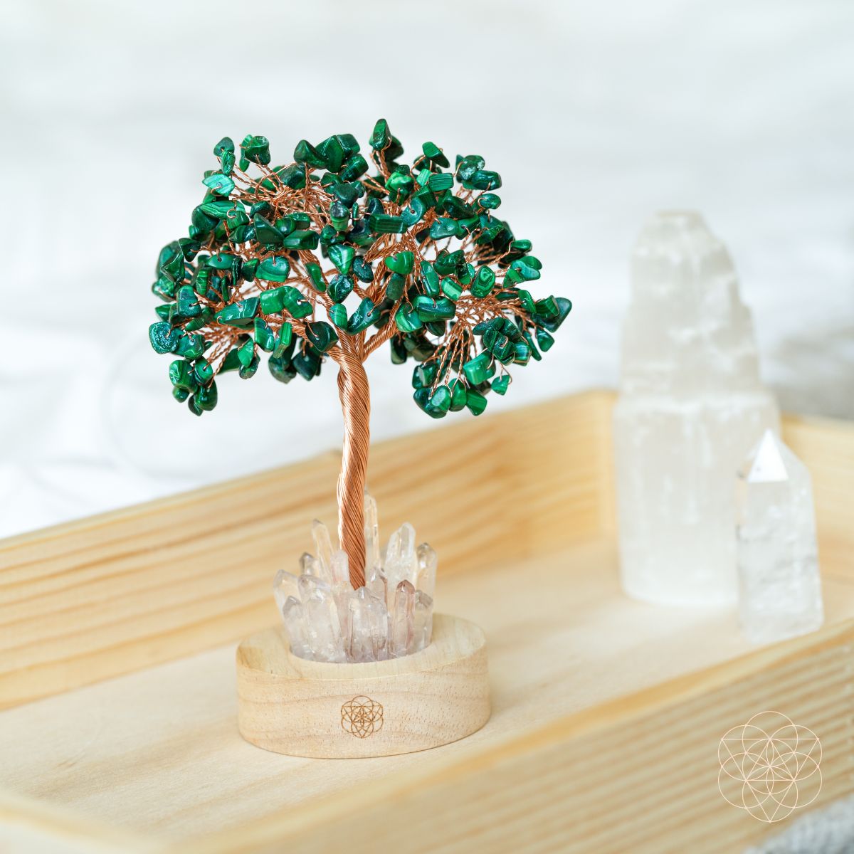 Close-up of malachite crystal tree lamp on light wood with teal branches and clear crystal base.
