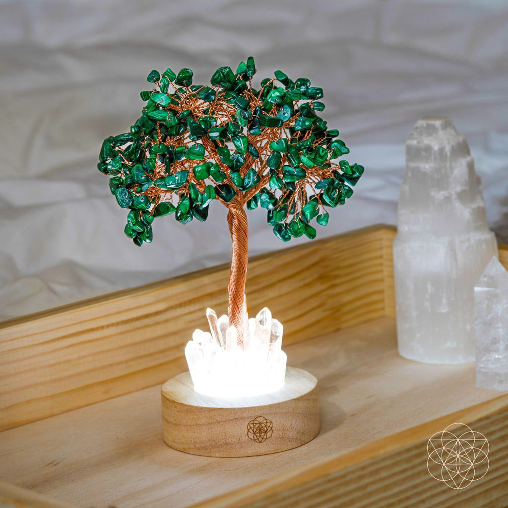 Malachite crystal tree lamp with teal branches and copper trunk beside clear quartz crystal.
