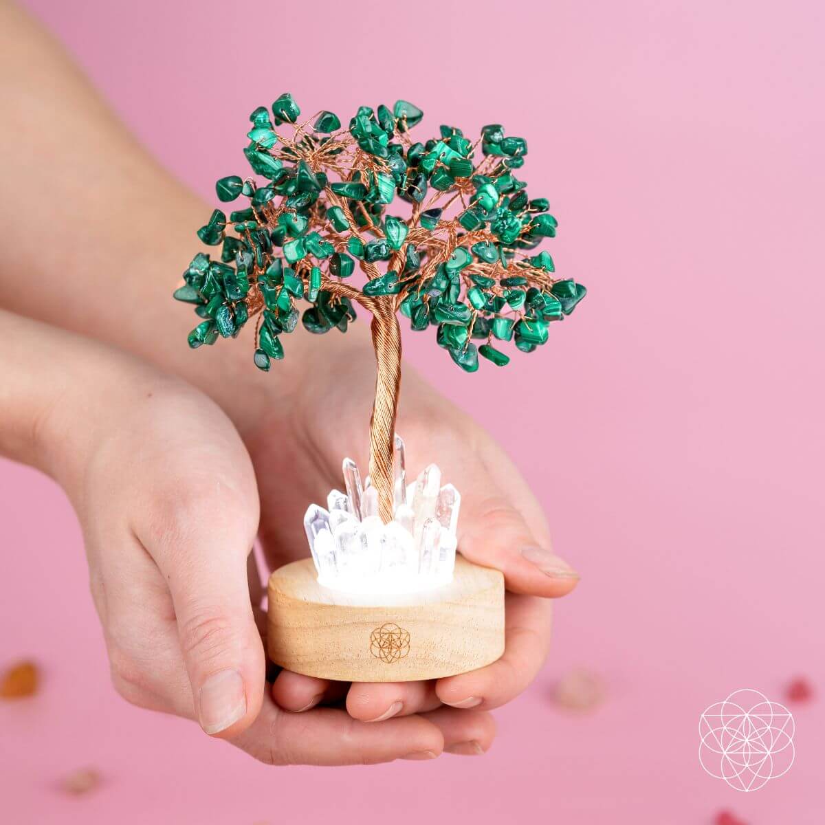 Teal-green malachite crystal tree lamp held close-up with clear crystal light on wooden base.