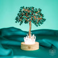 Malachite crystal tree lamp with teal branches, copper trunk, and clear crystal base on wood.
