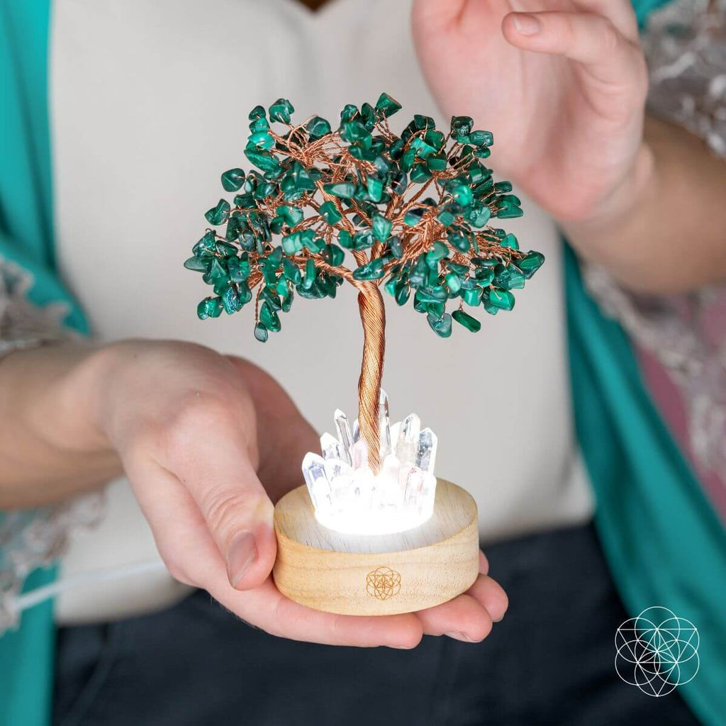 Crystal tree lamp held in hands: teal-green malachite branches, copper trunk, clear crystal light.