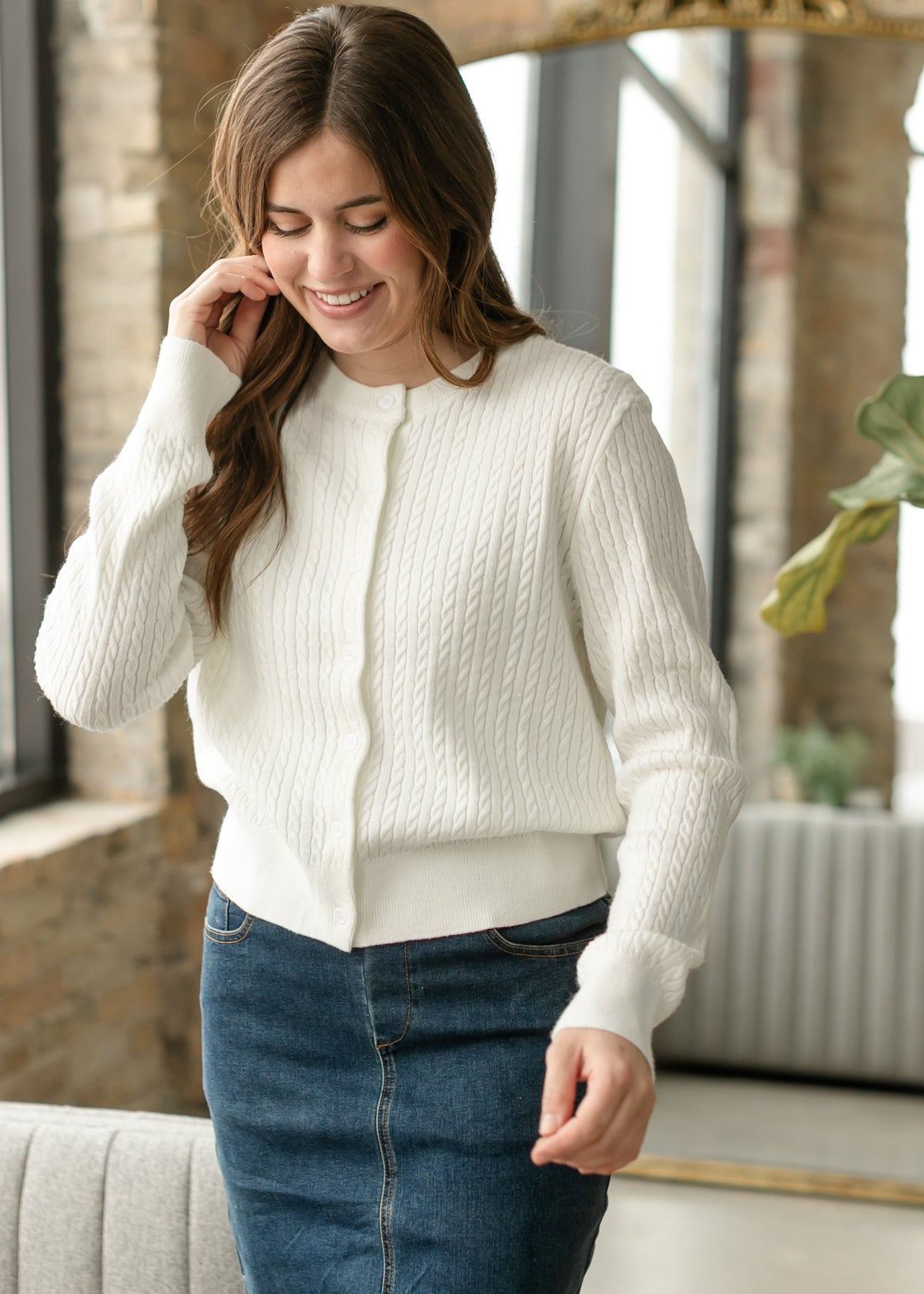 White button-up cable-knit cardigan with long sleeves, front button placket visible