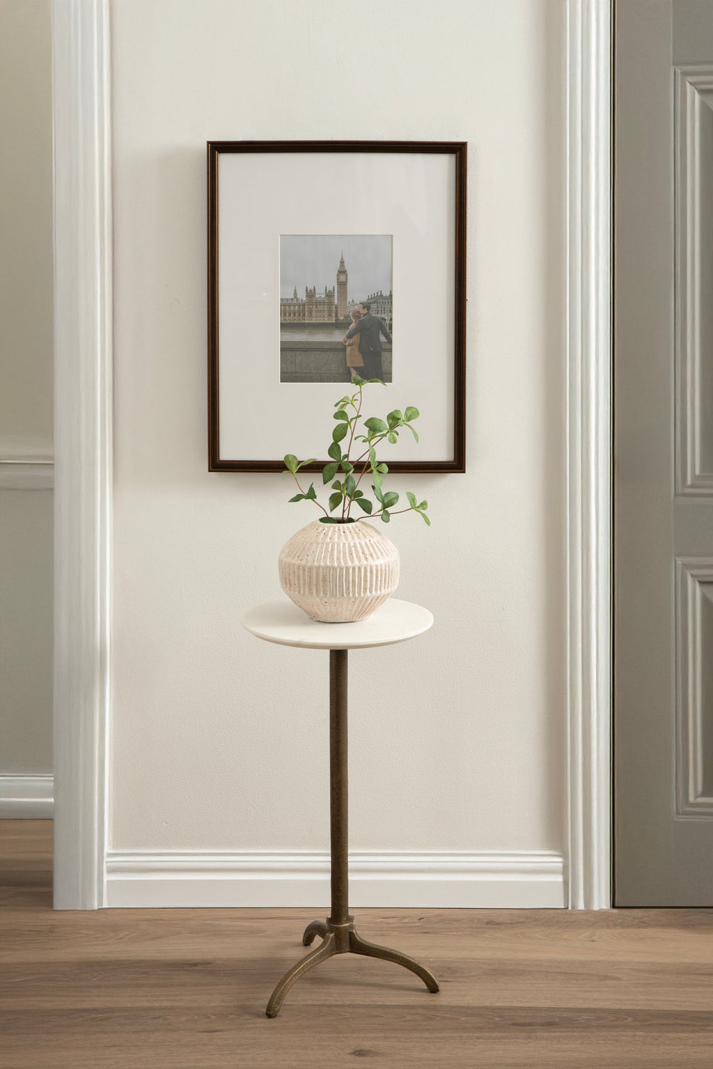 Round white marble side table with a small planter and plant on top