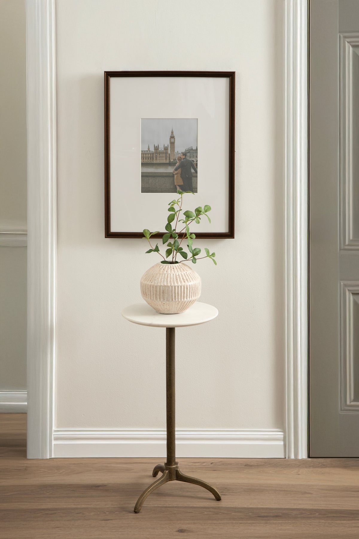 Round white marble side table with a small planter and plant on top