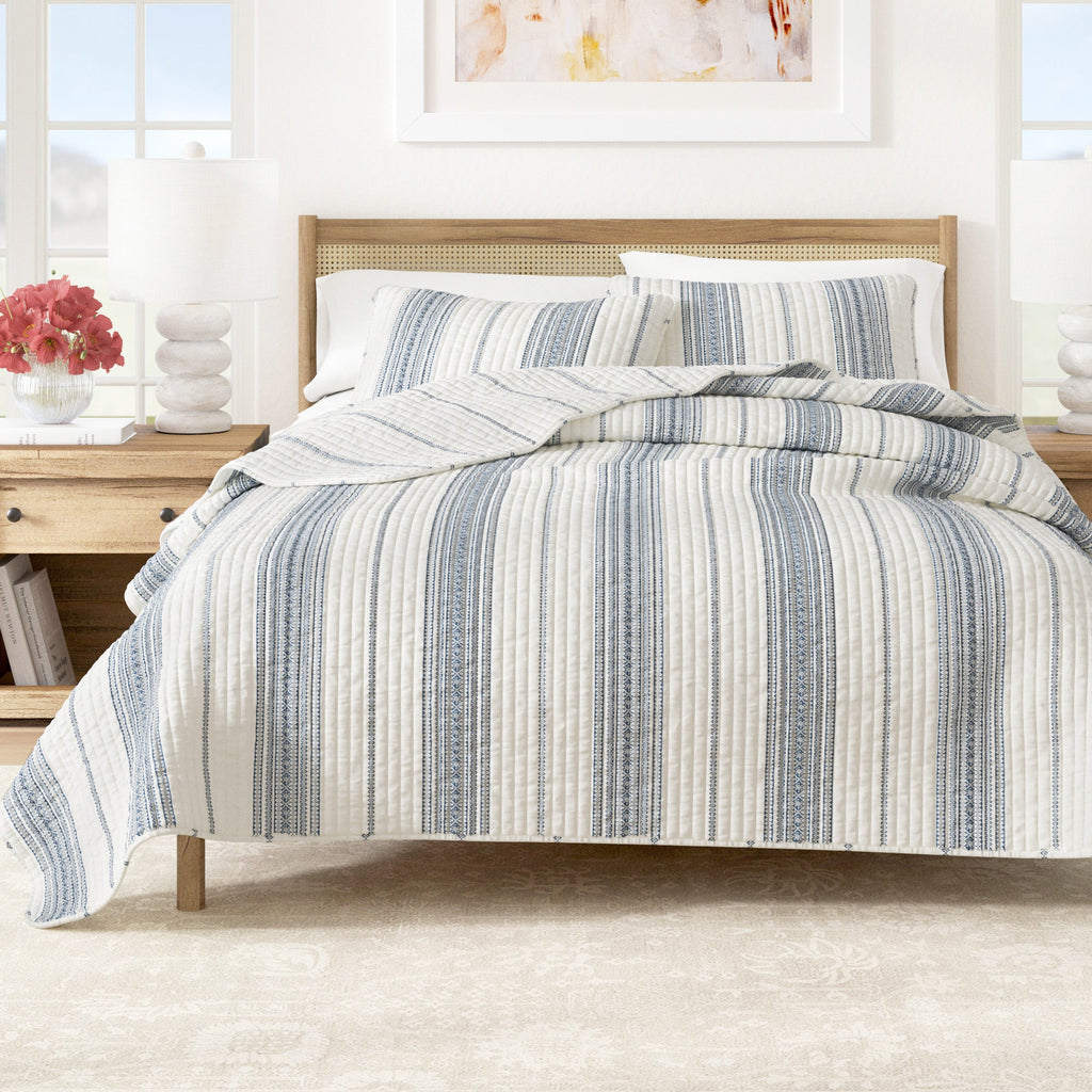 Striped quilt with cream base and navy vertical stripes, channel-quilted texture.