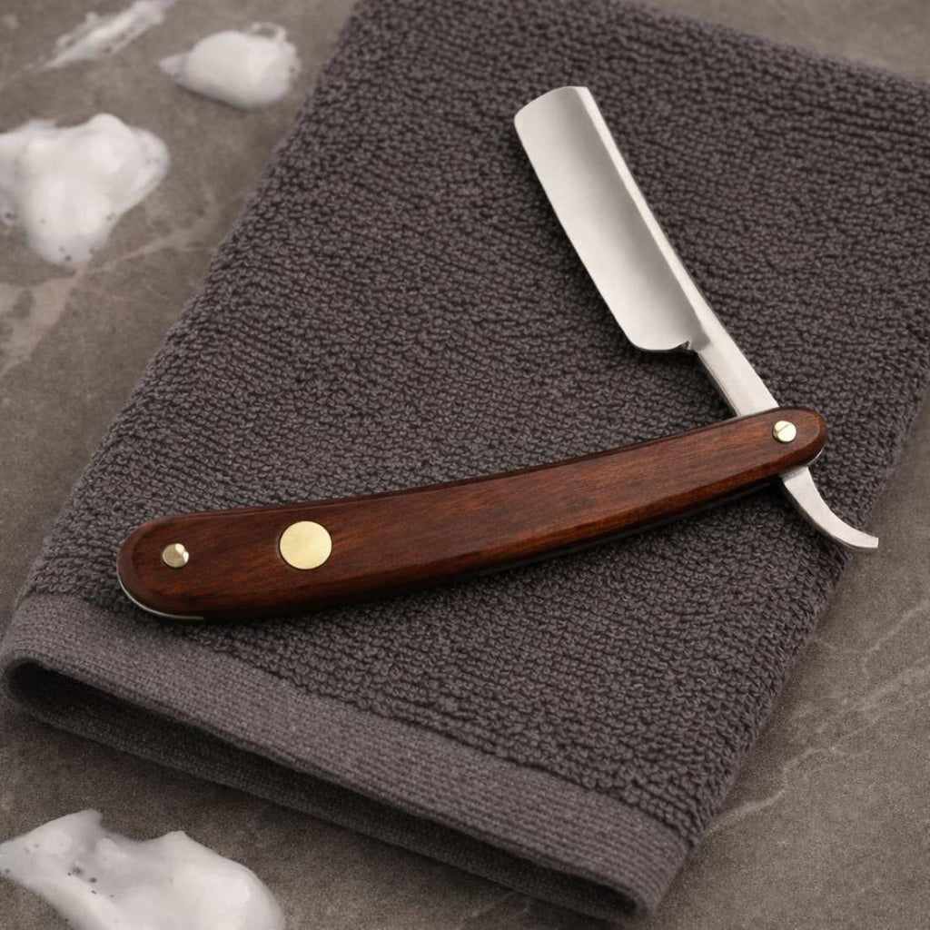 Straight razor with dark wood handle, silver blade, and two gold rivets