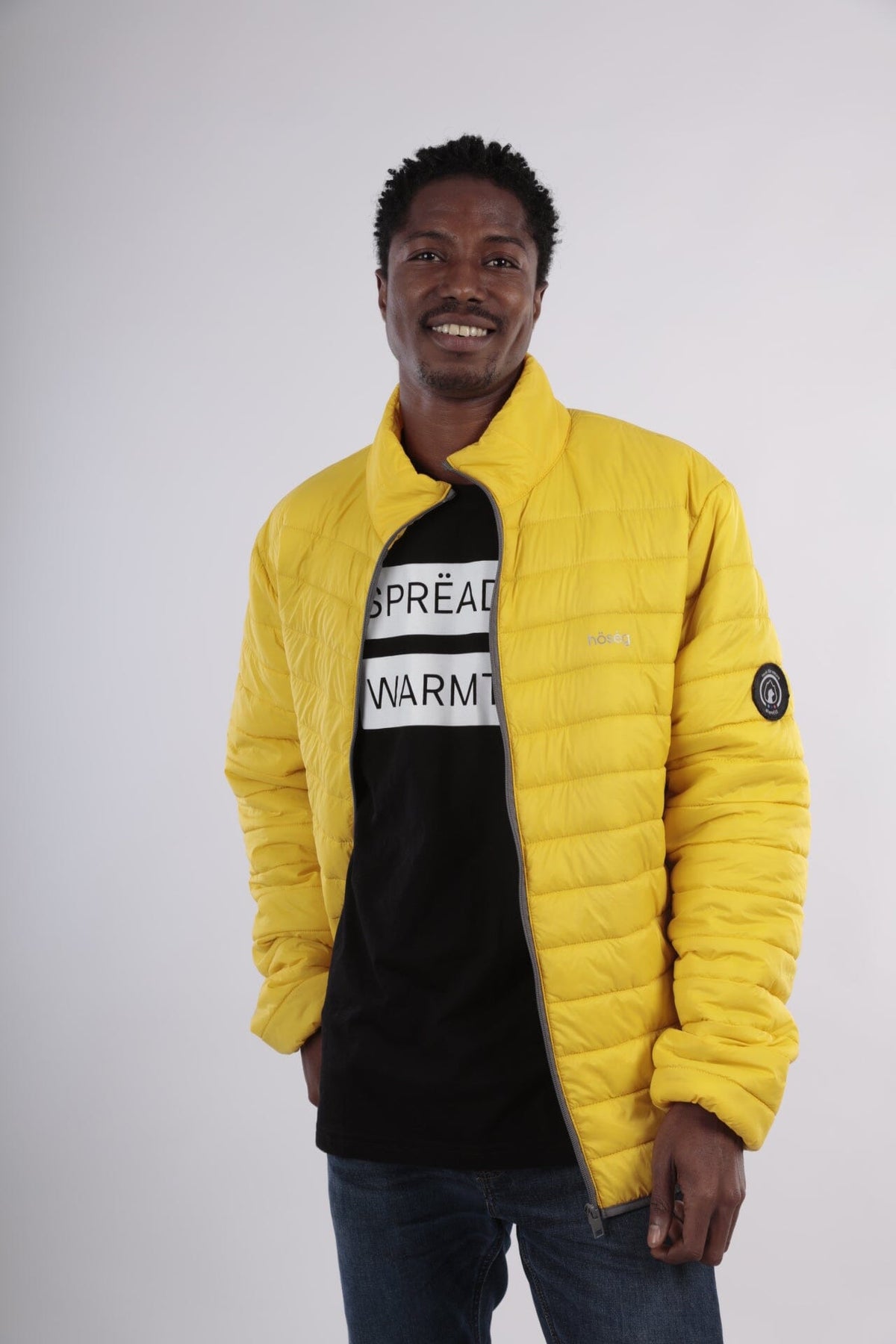 Yellow men’s puffer jacket with hood, full-zip front, quilted insulation, sleeve patch.