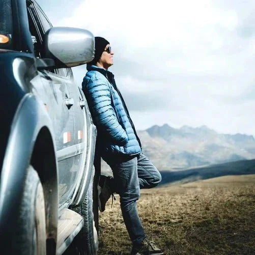 Blue men's puffer jacket worn outdoors with full-length zipper
