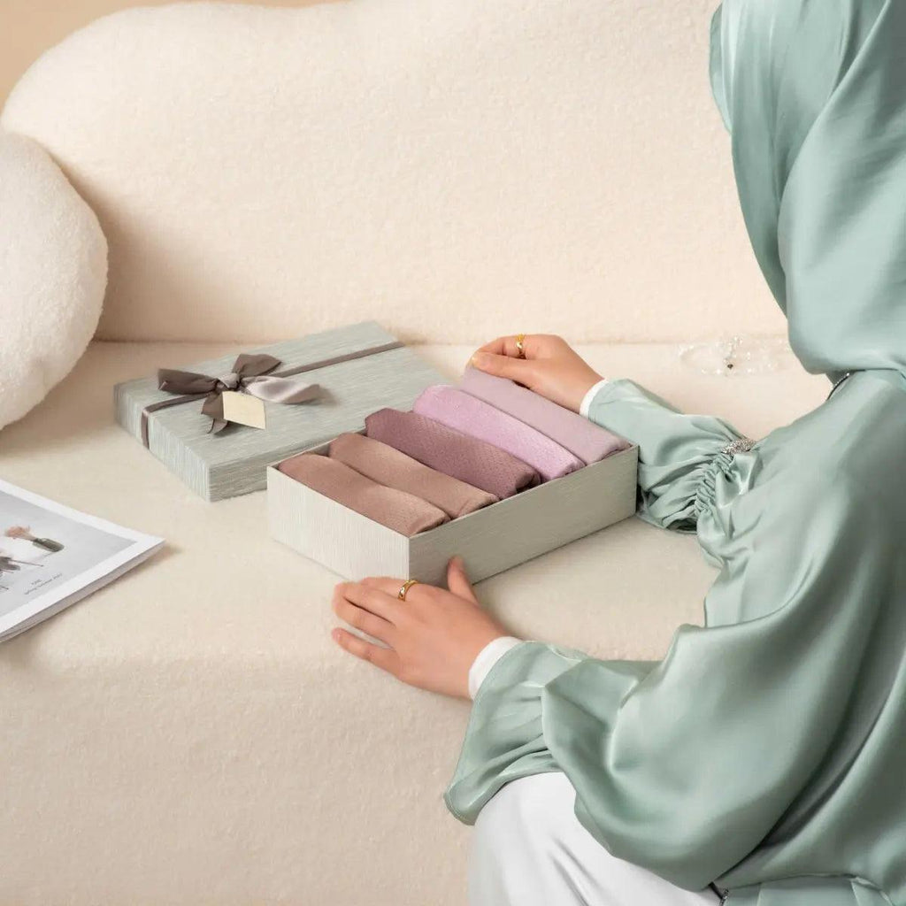 Textured hijab gift set box with lavender and mauve folds, hand placing scarf