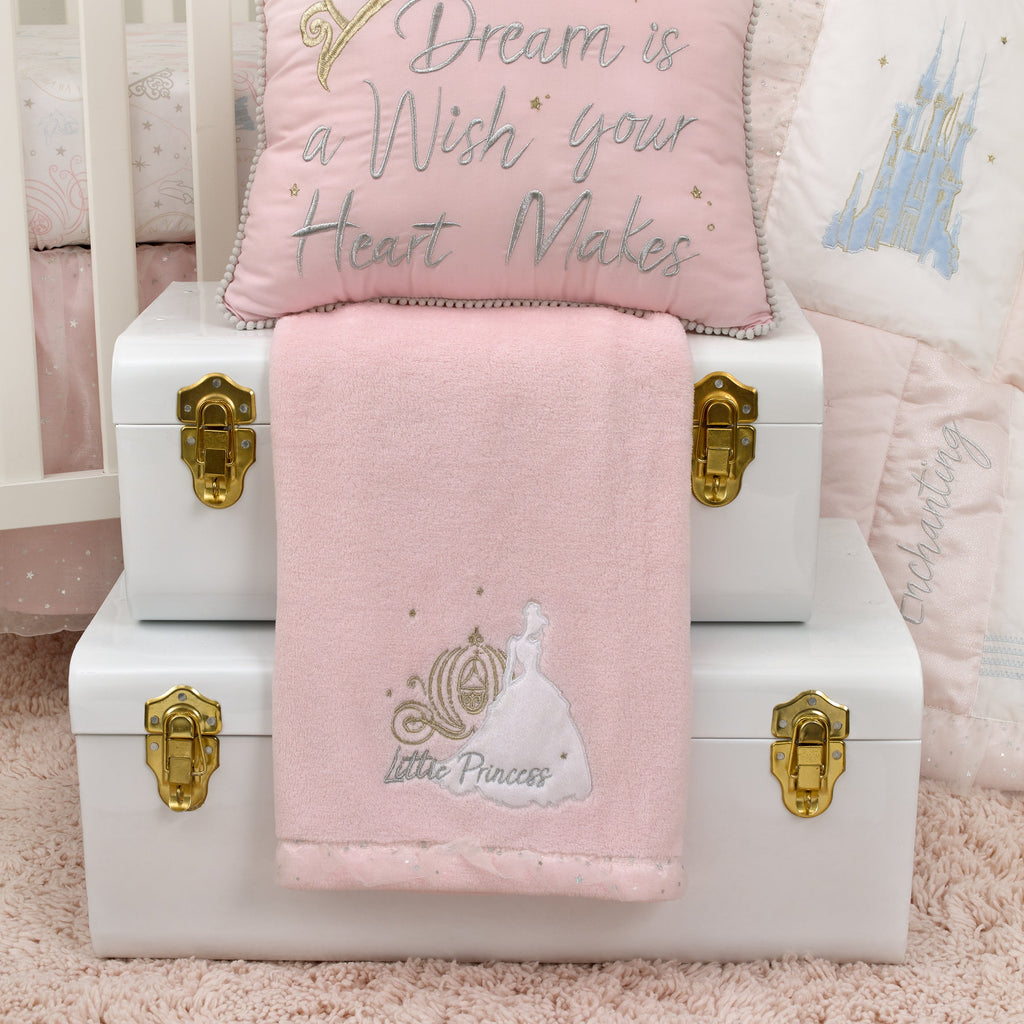 Pink baby blanket folded on a white crib, with embroidered Little Princess on front