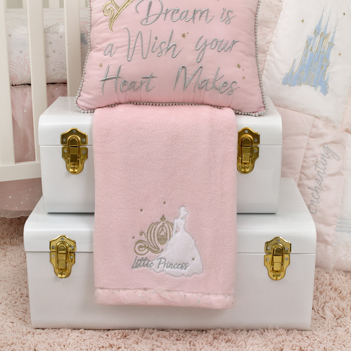 Pink baby blanket folded on a white crib, with embroidered Little Princess on front