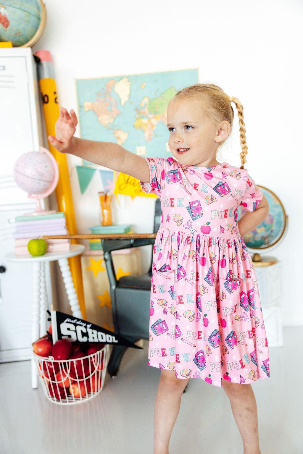 Pink short-sleeve twirl dress with front pocket and colorful graphic print