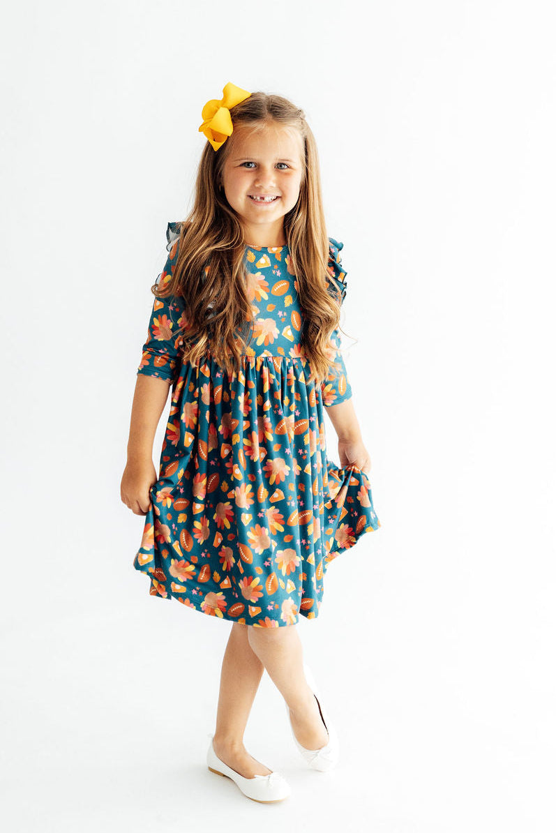 Girls’ teal twirl dress with 3/4 ruffle sleeves and gathered waist, orange pattern