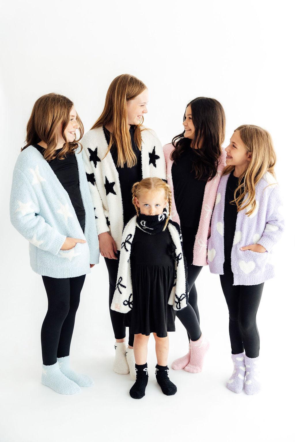 Light pink bow cozy cardigan worn by girl, fuzzy open-front style