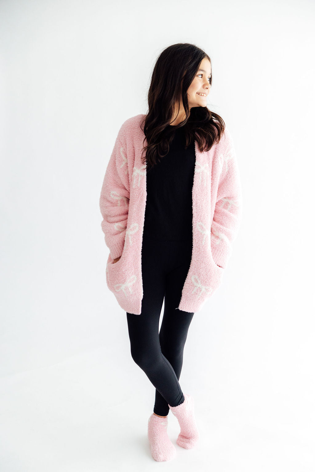 Light pink bow cozy cardigan, side view with open front over dark leggings