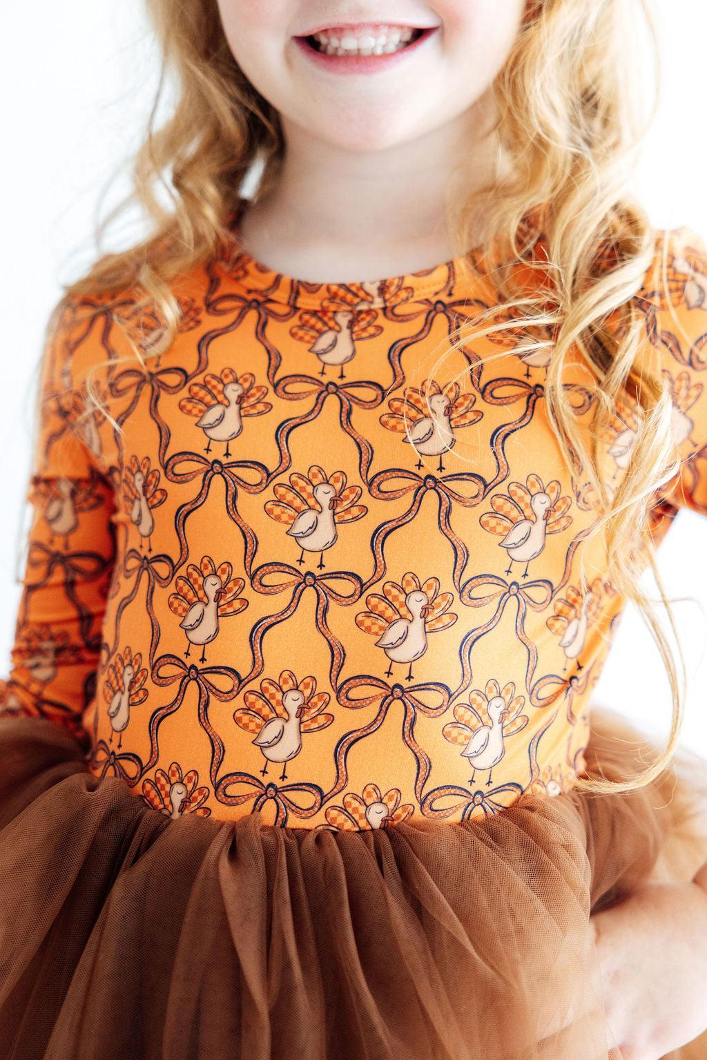 Orange turkey-print long-sleeve dress with brown tulle skirt, patterned bodice detail