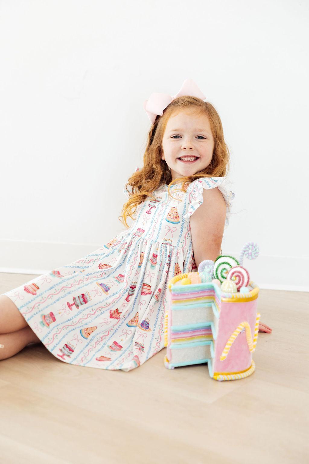 White cake-print twirl dress with flutter sleeves, knee length, gathered waist