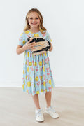 Light blue short-sleeve twirl dress with colorful softball and bow graphics, sneakers