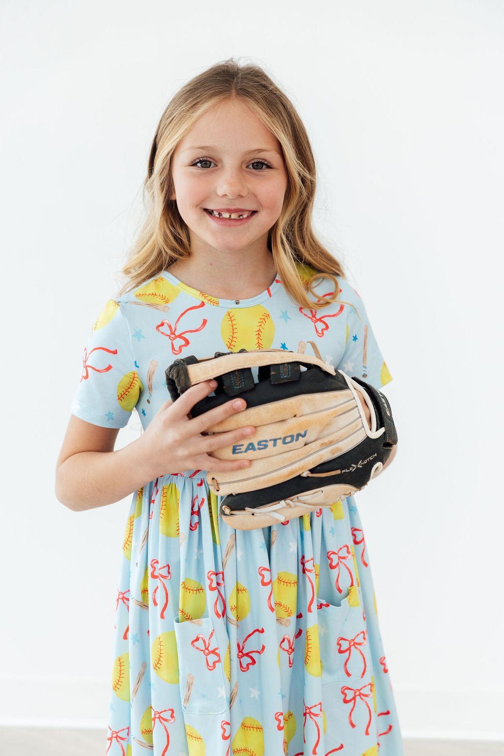 Light blue short-sleeve twirl dress with softball, bow, and ribbon pattern