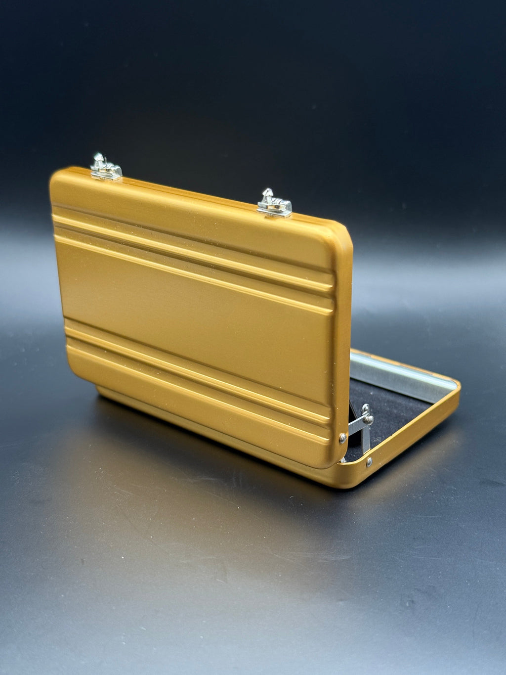 Gold mini briefcase with open lid and side handle, angled view.