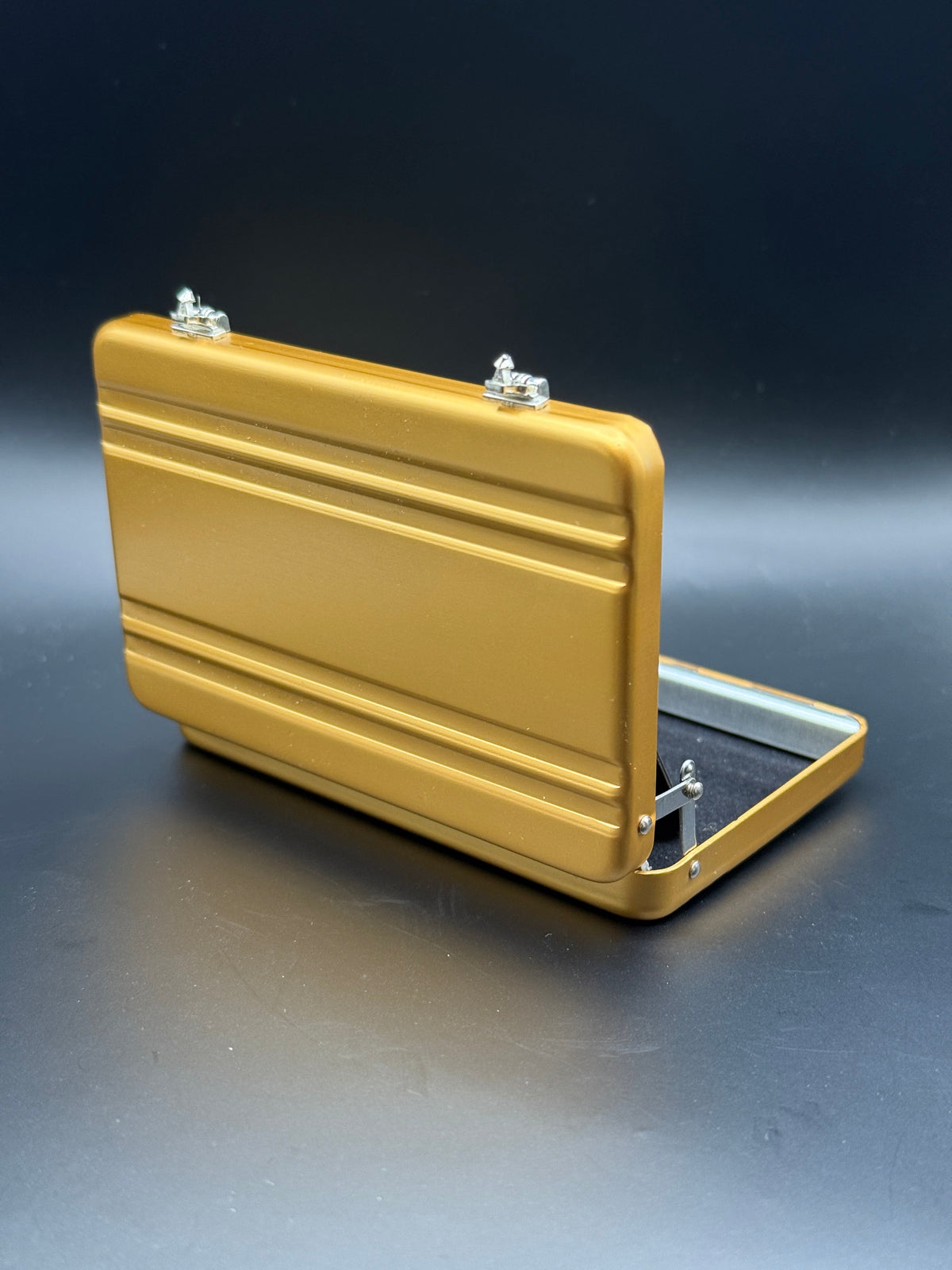 Gold mini briefcase with open lid and side handle, angled view.