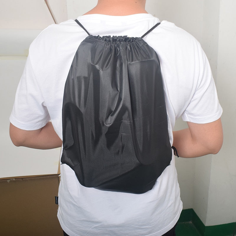 Adjustable black drawstring backpack with gray trim, worn on back