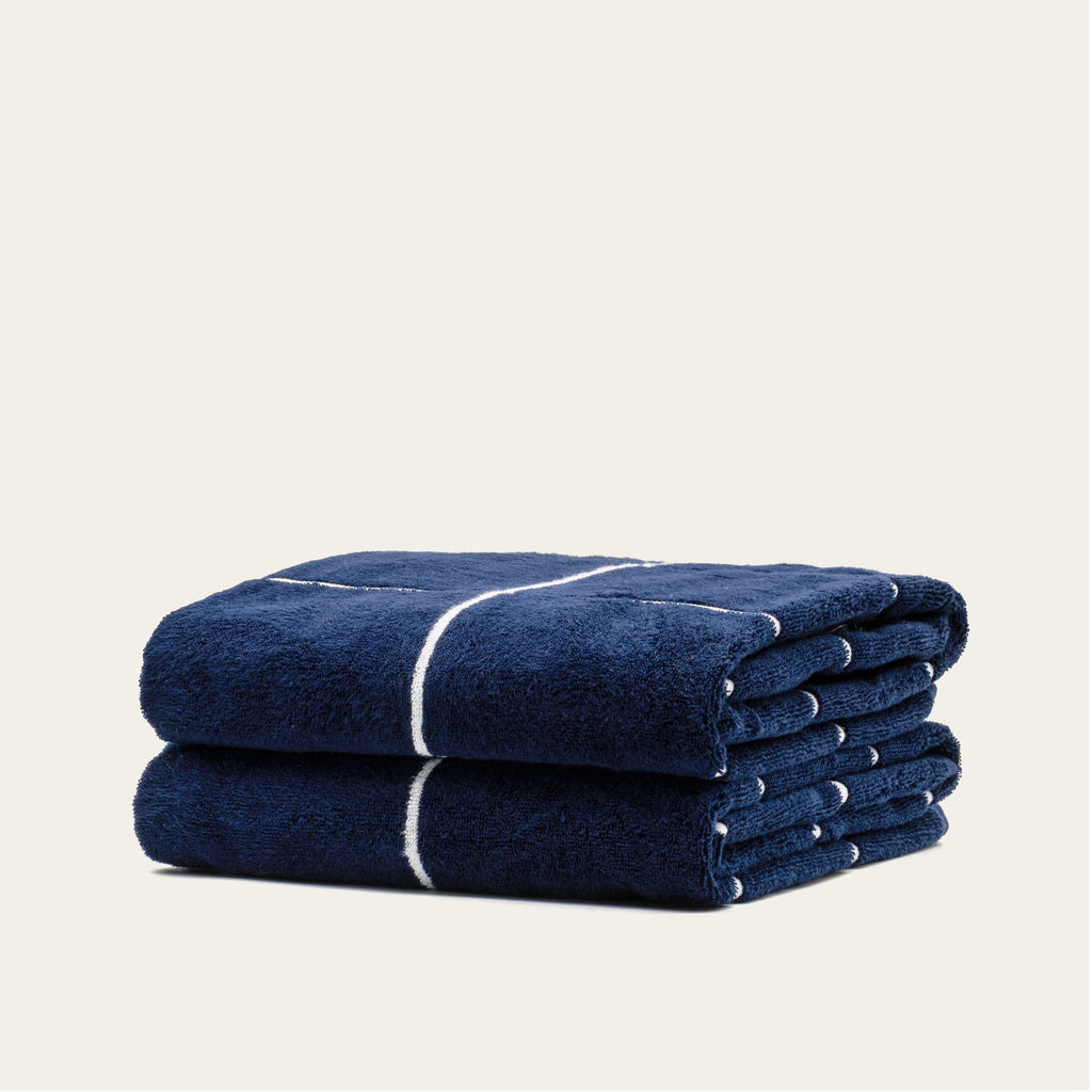 Rolled navy cotton towel with white stripe band, stacked view