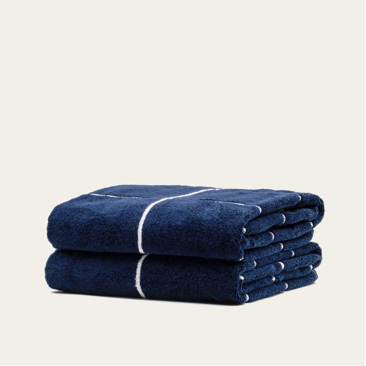 Rolled navy cotton towel with white stripe band, stacked view