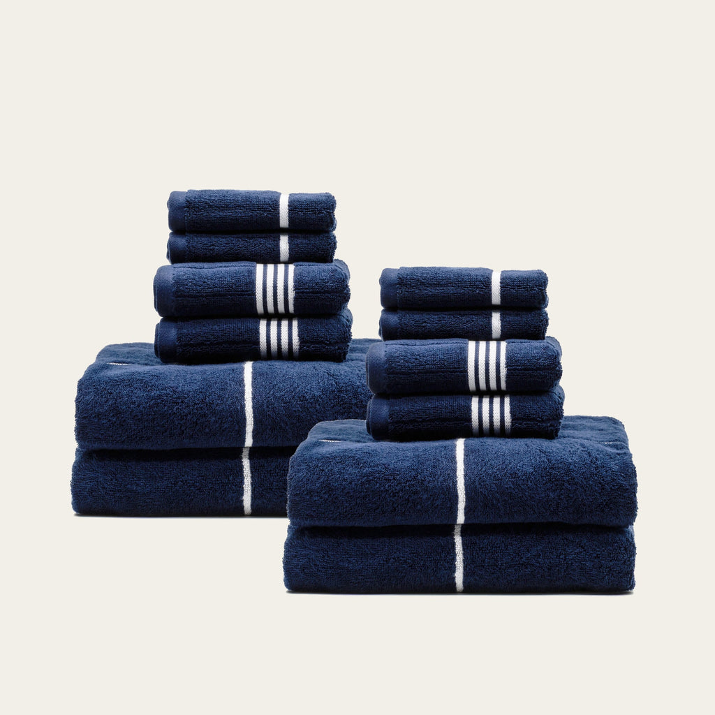 Assorted folded navy cotton towels with white stripe bands in stacks