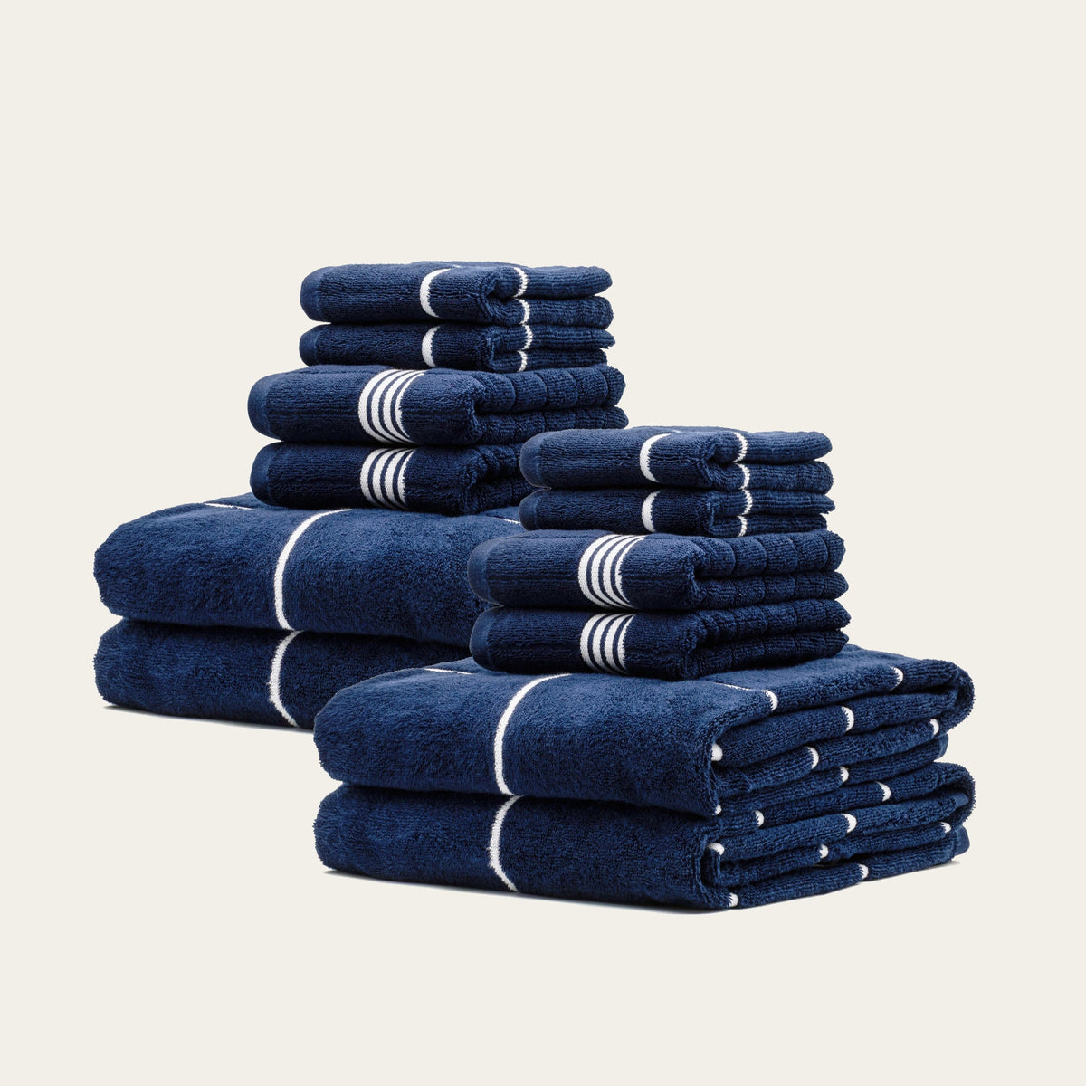 Multiple folded navy cotton towels with white stripe accents, stacked